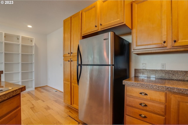 kitchen with light hardwood / wood-style floors and stainless steel refrigerator