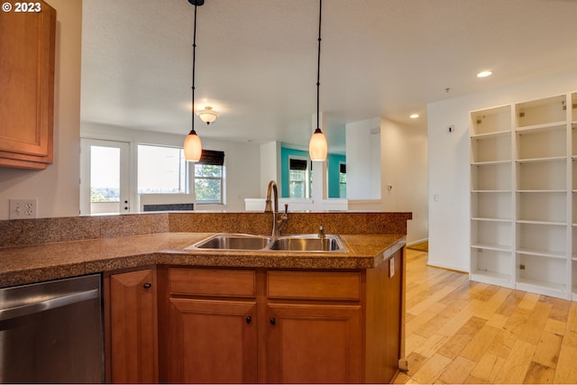 kitchen featuring stainless steel dishwasher, pendant lighting, a textured ceiling, sink, and light hardwood / wood-style flooring