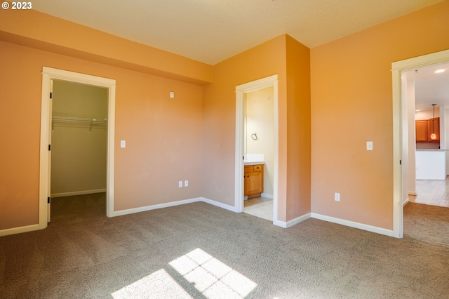 unfurnished bedroom with a walk in closet and light carpet