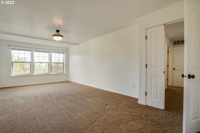 empty room with a textured ceiling and dark colored carpet