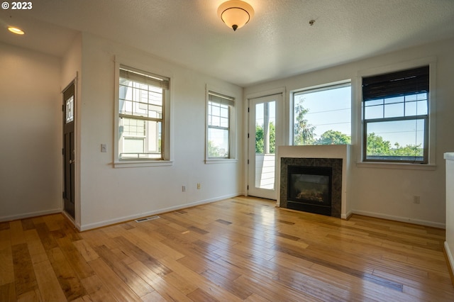 unfurnished living room with light hardwood / wood-style floors and a textured ceiling