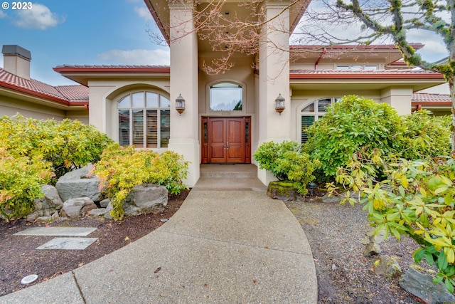 entrance to property with a tile roof and stucco siding