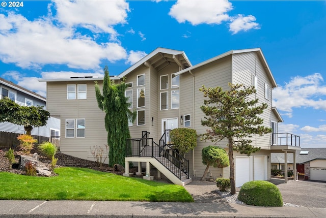 view of front of house featuring stairway, driveway, an attached garage, and a front yard