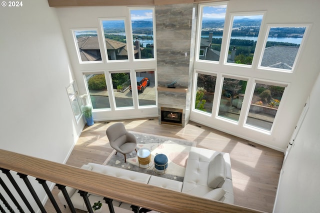 living area featuring a towering ceiling, visible vents, wood finished floors, and a fireplace