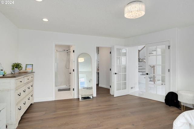 bedroom with a notable chandelier, recessed lighting, wood finished floors, and french doors