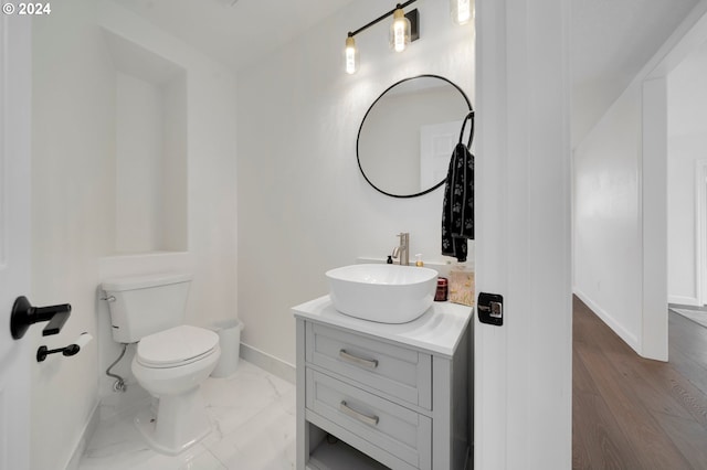 bathroom with marble finish floor, toilet, vanity, and baseboards