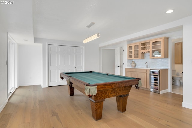 game room featuring beverage cooler, indoor wet bar, light wood-type flooring, and baseboards