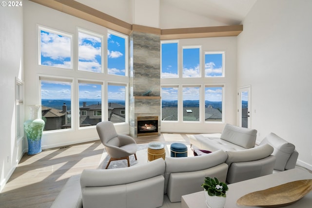 living room featuring a high end fireplace, high vaulted ceiling, baseboards, and wood finished floors