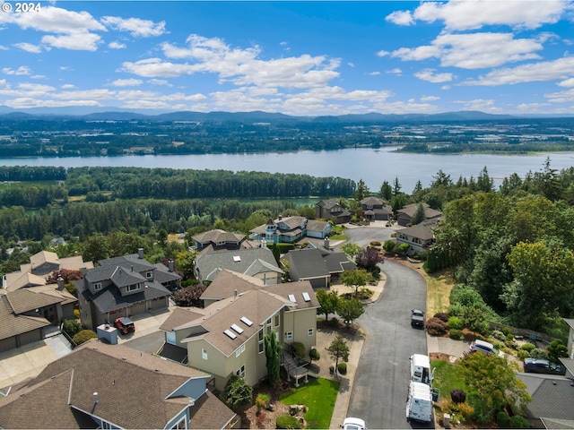 drone / aerial view with a residential view, a wooded view, and a water and mountain view