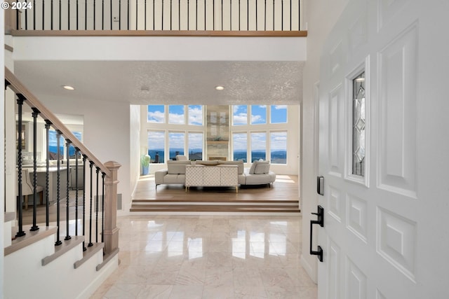 entryway featuring recessed lighting, stairs, a towering ceiling, a textured ceiling, and marble finish floor