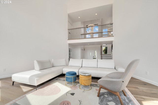 living room featuring baseboards, stairway, recessed lighting, a towering ceiling, and wood finished floors