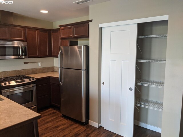 kitchen featuring appliances with stainless steel finishes, dark brown cabinets, and dark hardwood / wood-style flooring