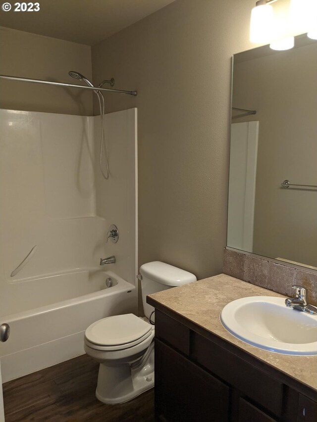 full bathroom featuring hardwood / wood-style floors,  shower combination, oversized vanity, and toilet