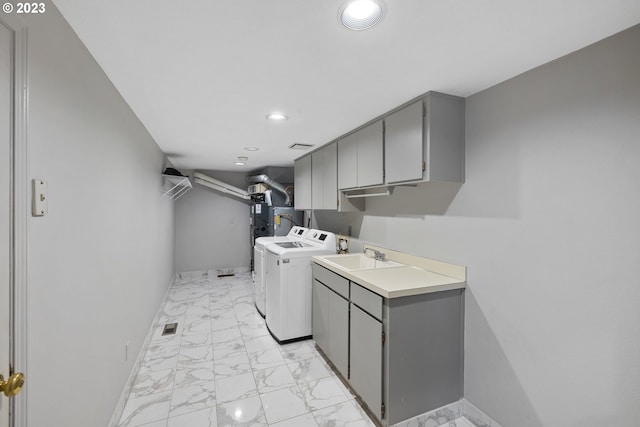 clothes washing area with cabinets, washing machine and clothes dryer, and sink