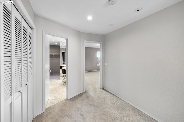 corridor featuring recessed lighting, baseboards, and light carpet