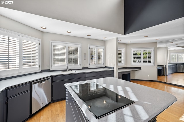 kitchen with a sink, light wood-style floors, dishwasher, and black stovetop