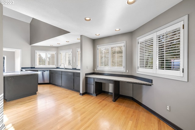 kitchen featuring stainless steel dishwasher, sink, light hardwood / wood-style flooring, and kitchen peninsula