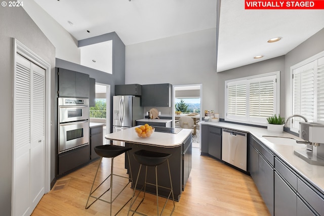 kitchen with a center island, a breakfast bar area, light wood-type flooring, stainless steel appliances, and a sink