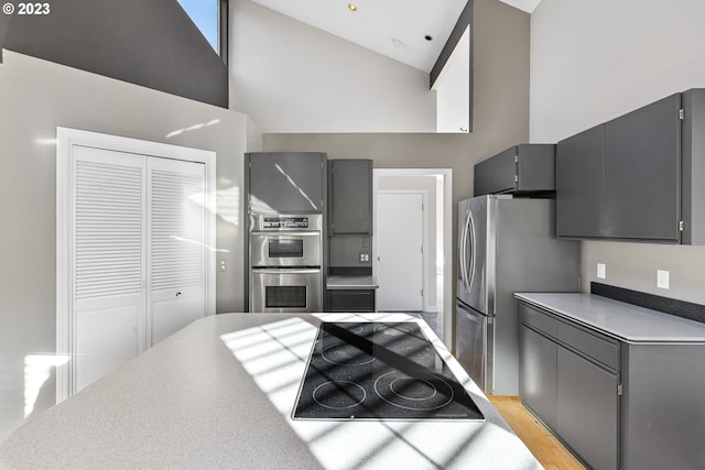 kitchen featuring gray cabinets, appliances with stainless steel finishes, high vaulted ceiling, and light hardwood / wood-style flooring