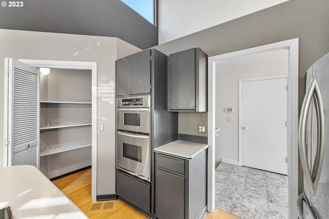 kitchen with light countertops, light wood finished floors, gray cabinets, and appliances with stainless steel finishes