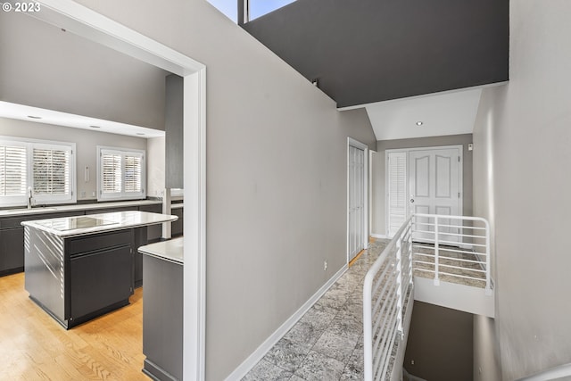 hall with a sink, baseboards, and lofted ceiling