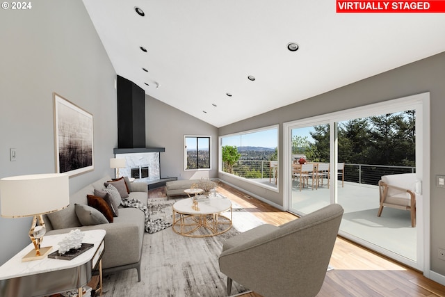 living room with recessed lighting, a fireplace, high vaulted ceiling, and wood finished floors