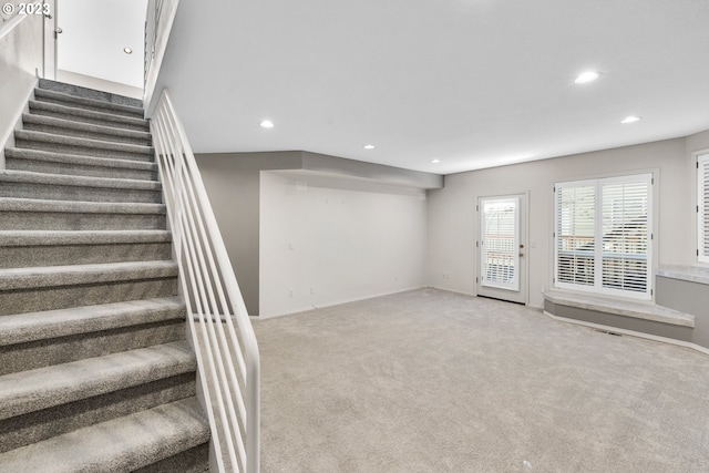 unfurnished living room featuring recessed lighting, stairway, light carpet, and baseboards