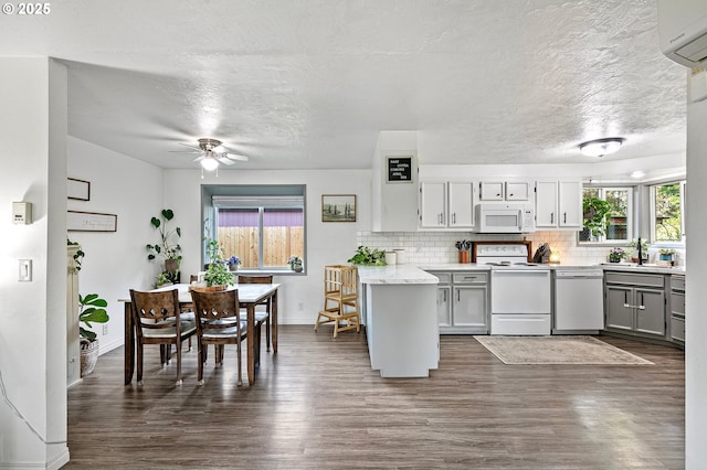 kitchen with white appliances, ceiling fan, decorative backsplash, dark wood finished floors, and an AC wall unit