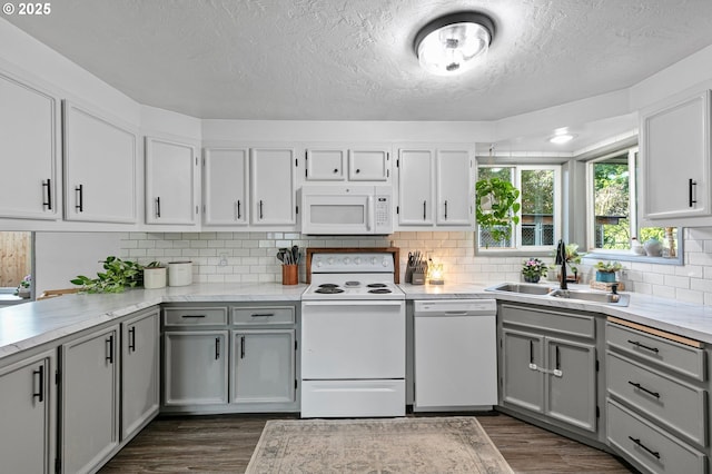 kitchen with white appliances, a sink, dark wood-type flooring, gray cabinetry, and a textured ceiling