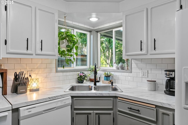 kitchen with white appliances, a sink, decorative backsplash, and white cabinets
