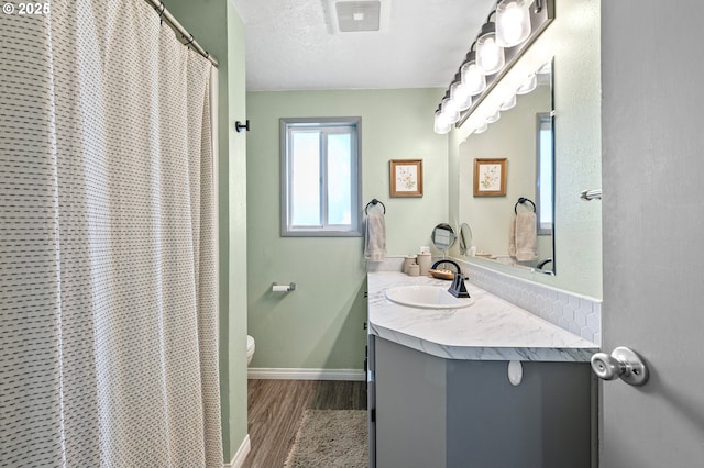 bathroom with wood finished floors, toilet, vanity, and baseboards