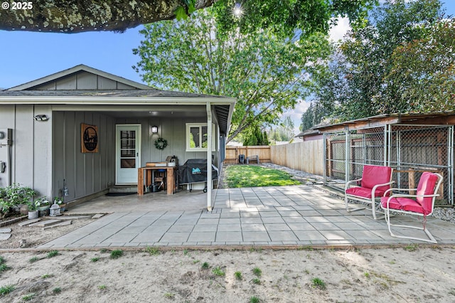 back of house with board and batten siding, a fenced backyard, and a patio area