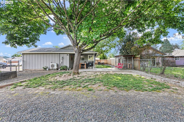 view of front of house featuring board and batten siding, a cooling unit, a fenced backyard, and a patio area