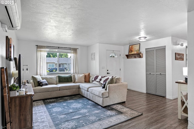 living area with an AC wall unit, wood finished floors, a textured ceiling, and baseboards