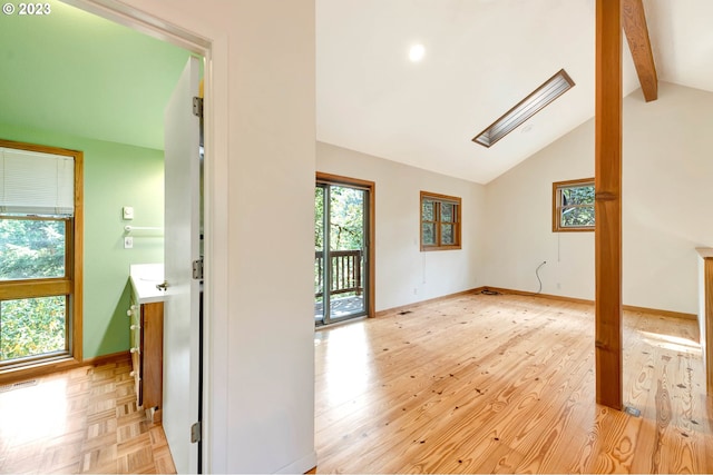 spare room featuring light parquet flooring, lofted ceiling with beams, and a wealth of natural light