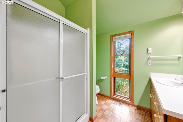 bathroom with parquet flooring, toilet, vanity, and an enclosed shower