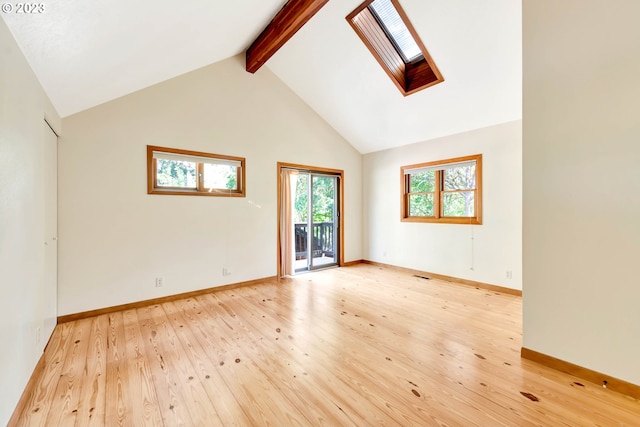 unfurnished room featuring a skylight, light hardwood / wood-style floors, high vaulted ceiling, and beamed ceiling