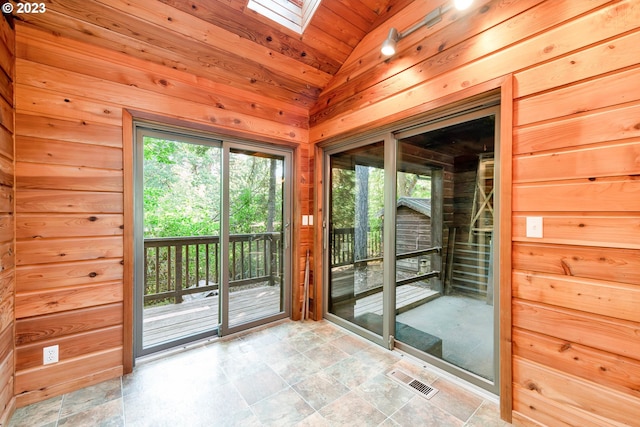 entryway featuring lofted ceiling with skylight, wood walls, wooden ceiling, and light tile floors