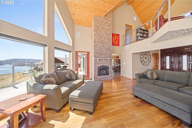 living room featuring a stone fireplace, a water and mountain view, high vaulted ceiling, and wooden ceiling