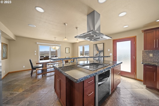 kitchen featuring an island with sink, black electric stovetop, dark tile flooring, island exhaust hood, and pendant lighting