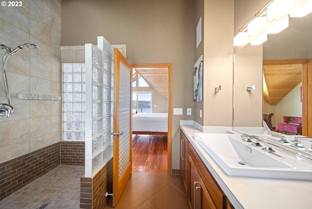 bathroom with tile flooring, a tile shower, and vanity