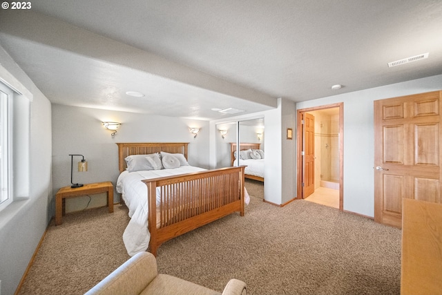 bedroom featuring connected bathroom and light colored carpet