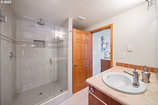 bathroom with vanity, a textured ceiling, tile floors, and a shower with shower door