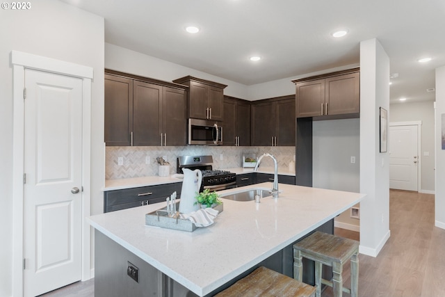 1647 N Millican Creek St, Lafayette, OR 97127 - kitchen with stainless steel microwave, range with gas stovetop, decorative backsplash, dark brown cabinetry, and an island with sink