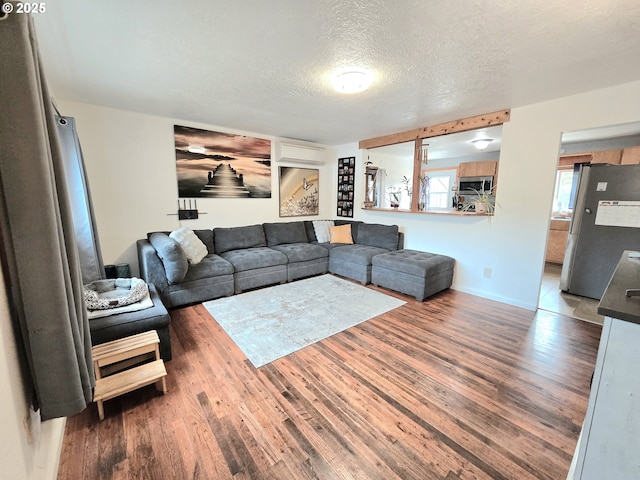 2951 NE Yount Ave, Roseburg, OR 97470 - living area with wood finished floors, a textured ceiling, a wall mounted AC, and baseboards