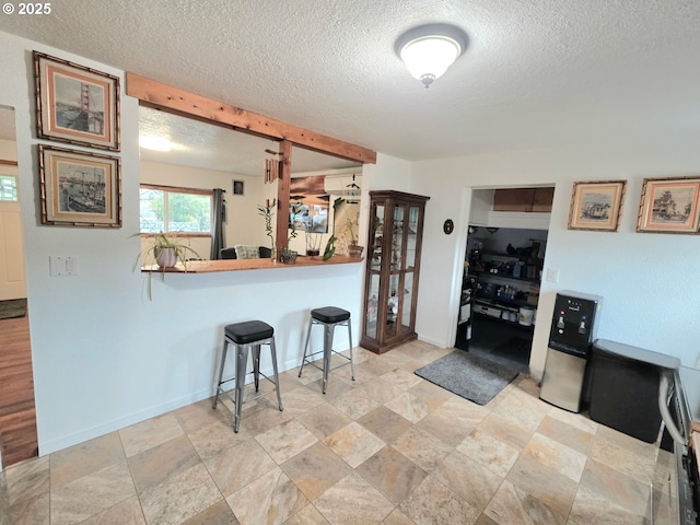 2951 NE Yount Ave, Roseburg, OR 97470 - kitchen with a textured ceiling, a breakfast bar area, stone finish flooring, and baseboards