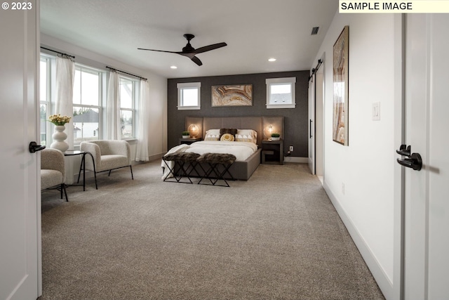 carpeted bedroom with a barn door and ceiling fan