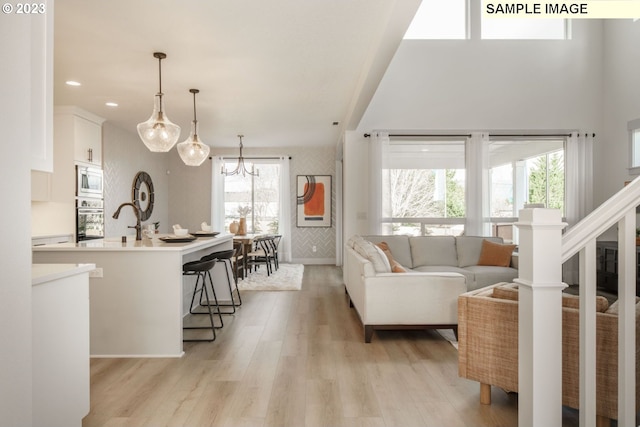 living room featuring sink, a notable chandelier, and light hardwood / wood-style floors