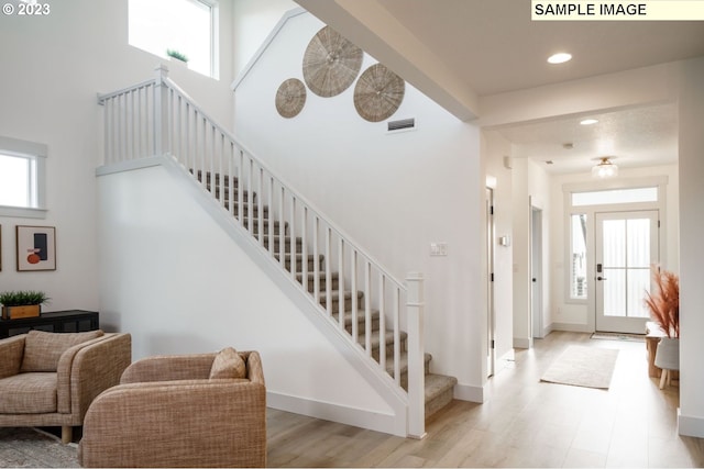 entrance foyer with a towering ceiling and light hardwood / wood-style floors