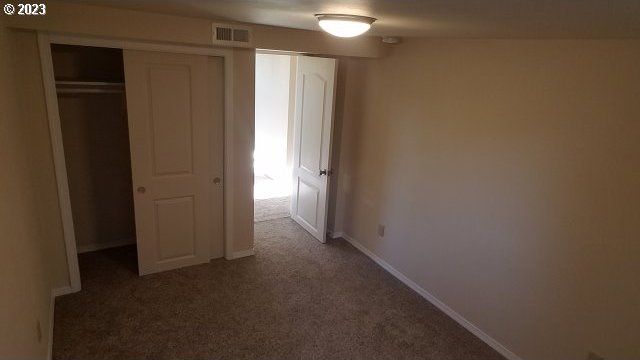 unfurnished bedroom with dark colored carpet and a closet